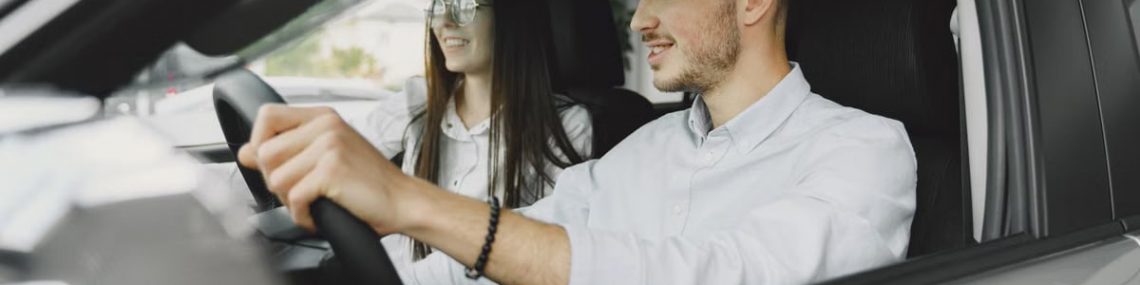 A young couple smiling while driving together in a modern car interior.